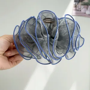 Macro view of grey organza ruffle hair claw clip with layered sheer textured fabric