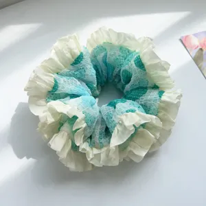 Close-up of a mint green heart mesh scrunchie featuring layered white ruffles