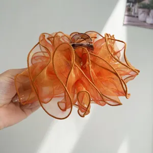Detail shot of a fashionable orange mesh ruffle hair claw clip with elegant bow design