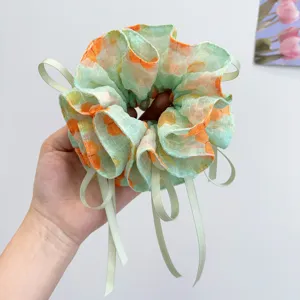 Close-up detail of forest style floral printed scrunchie with light green ribbons