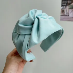 Vista detallada de una diadema de tela anudada azul claro con textura plisada suave