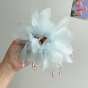 Primo piano di un elastico in organza azzurro con delicati ciondoli in cristallo rosa.
