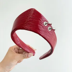 Primo piano dettagliato della fascia in pelle rossa testurizzata con anelli d'argento.