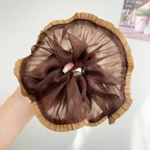 Detail van de geplooide gaastectuur en het gelaagde ontwerp van deze bruine scrunchie.