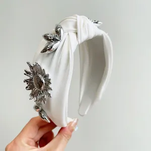 Close-up of white knotted wide headband featuring silver metallic flower decorations