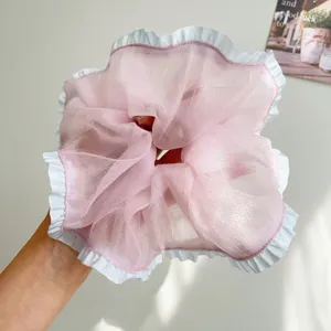 Gedetailleerde macro-opname van een elegante roze mesh scrunchie met witte ruches details