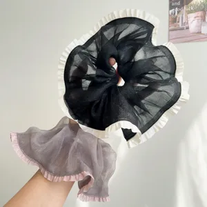 Detail van twee grote organza scrunchies met ruches in zwart en grijs voor het haar.