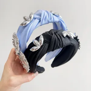 Detailed view of knotted wide headbands with metallic silver flower decorations