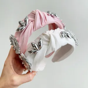 Close-up of metallic flower details on pink and white knotted wide headbands for women.