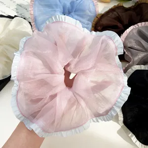 Close-up van grote roze organza scrunchie met lichtblauwe ruches aan de randen voor haarstijl