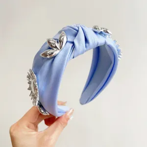 Detail of light blue satin knotted headband decorated with metallic silver floral ornaments