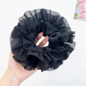 Dettaglio di un grande elastico nero a balze in rete tenuto in mano per la misura.