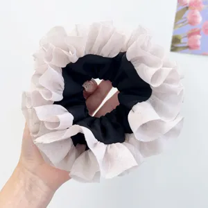 Dettaglio di un elastico per capelli in pizzo rosa stile balletcore in mano