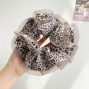 Close-up detail of oversized leopard print scrunchie with elegant pleated lace edges