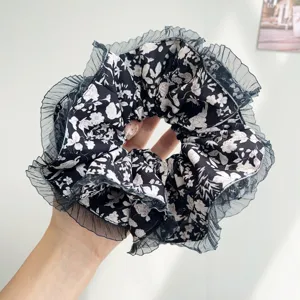 Close-up of large floral pleated scrunchie featuring elegant grey mesh trim detail