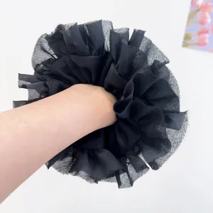 Dettaglio di un grande elastico in pizzo nero indossato al polso per uno stile ballet.