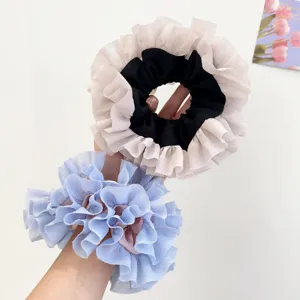 Dettaglio ravvicinato di elastici per capelli in pizzo arricciato in blu e beige