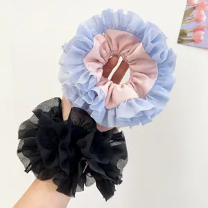 Dettaglio ravvicinato di elastici per capelli in pizzo rosa, azzurro e tulle nero