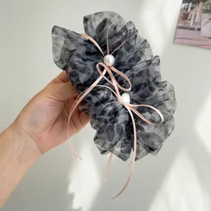 Détail d'une pince à cheveux léopard avec rubans roses et perles élégantes