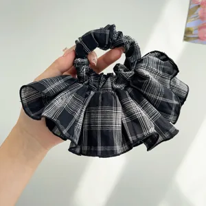 Detailed view of the black and white plaid ruffle scrunchie showing soft fabric texture