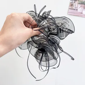Detail view of a large black and white striped organza bow hair claw clip held by hand
