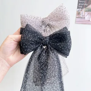 Detalle de pinzas para el pelo grandes con lazo de malla con estampado leopardo.