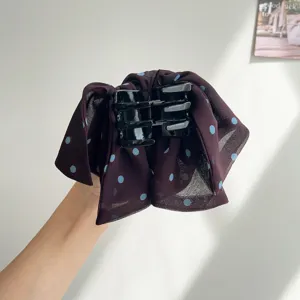 Vue détaillée d'une pince à cheveux en mousseline à pois violet foncé avec design en résille