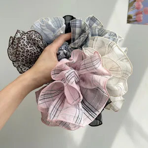 Detailed view of oversized plaid and leopard print ruffled hair scrunchies