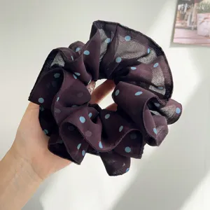 Détail d'un grand chouchou en maille violet foncé avec pois bleus et bords volantés