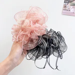 Close-up of large organza ruffled bow hair claw clips in pink and black stripes.