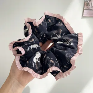 Gros plan d'un chouchou noir avec motif de cheval et bordure en dentelle rose