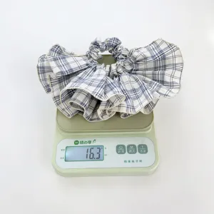 Close-up of a plaid ruffled scrunchie on a scale showing a weight of 16.3 grams