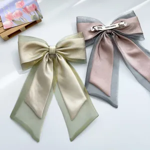Detailed view of shimmering organza bow hair clip with elegant ribbons and metal clip