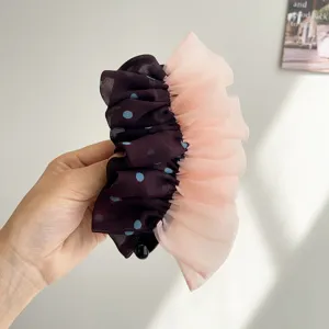 Vue détaillée de la pince à cheveux à pois en tulle et volants en pêche et noir