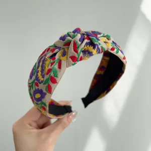 Primer plano de una diadema bohemia con bordado floral vibrante y diseño anudado.
