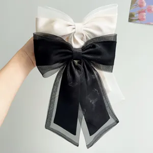Detailed view of elegant large organza hair bows with ribbons in black and cream white