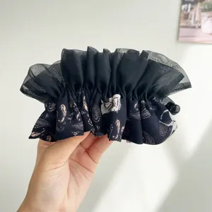 Gros plan détaillé montrant le tissu en mesh noir et le motif paisley du chouchou