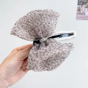 Detalle de una pinza para el pelo con lazo de malla de leopardo y centro de strass.