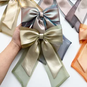 Detailed close-up of elegant organza iridescent bow hair clip with long ribbons in light green