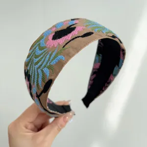 Detailed macro shot of a bohemian wide headband featuring intricate ethnic floral embroidery