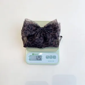 Gros plan montrant le poids de 12,5 g d'une pince à cheveux en maille léopard chic