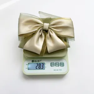 Detail showing an elegant organza bow hair clip weighing 28.3g on a digital scale.