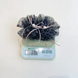 Détail d'une pince à cheveux en tulle léopard avec rubans roses sur une balance