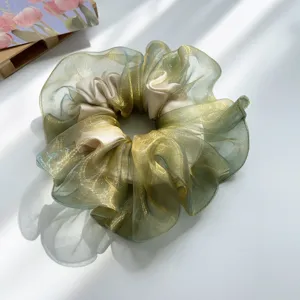 Detailansicht eines schimmernden hellgrünen Haargummis aus Organza mit Glanzeffekt.