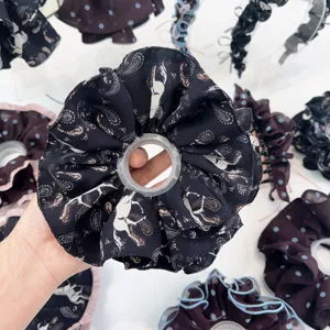 Vue détaillée d'un chouchou noir avec motif de cheval blanc et paisley