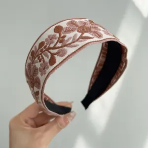 Close-up of a bohemian embroidered wide fabric headband with intricate floral patterns