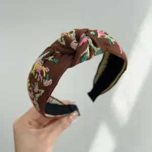 Primer plano de una diadema de tela anudada estilo bohemio con bordados flores