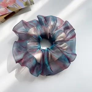 Detail eines schillernden Organza-Haargummis mit schimmernden Texturen in Blau und Rosa.