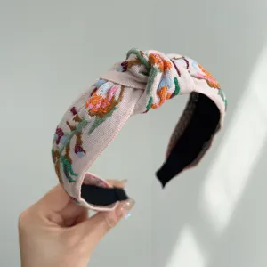 Detalle de bordado floral bohemio en una elegante diadema de tela anudada para mujer