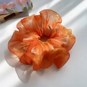 Nahaufnahme eines leuchtend orangefarbenen, schillernden Organza-Haargummis mit Schatten.